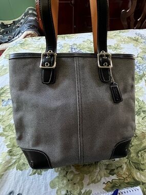 Coach bag. Gray and white with black leather bottom and handles. Has side tag.